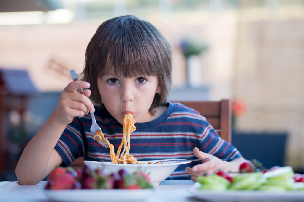 Little boy eating a bowl of spaghetti