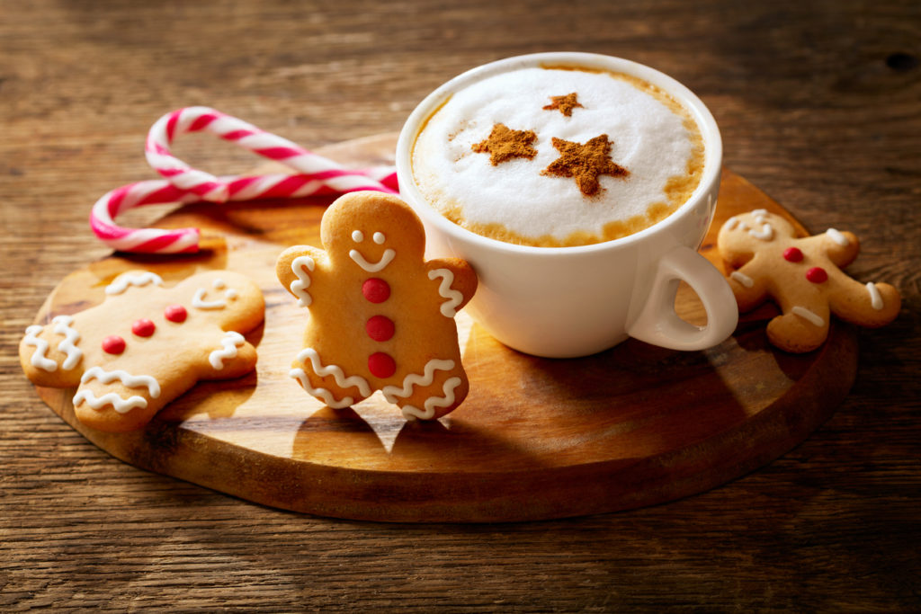 Cup of cappuccino coffee with stars drawing and gingerbread cookie