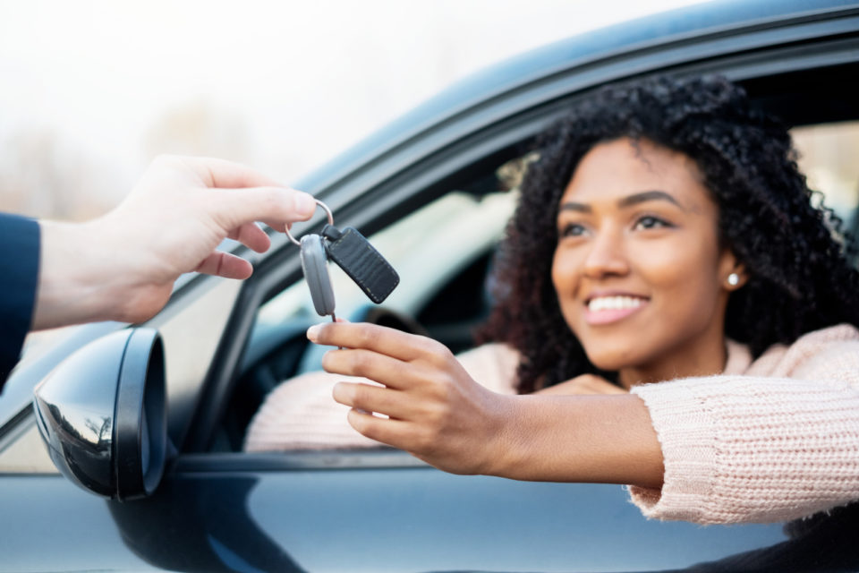 Happy woman receiving the keys to her new car.