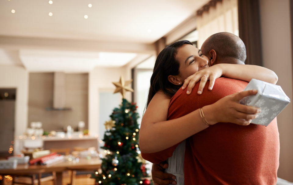 Shot of a happy young couple exchanging Christmas gifts at home