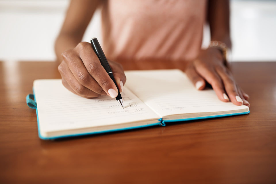 Cropped shot of a woman checking off tasks on a chore list at home