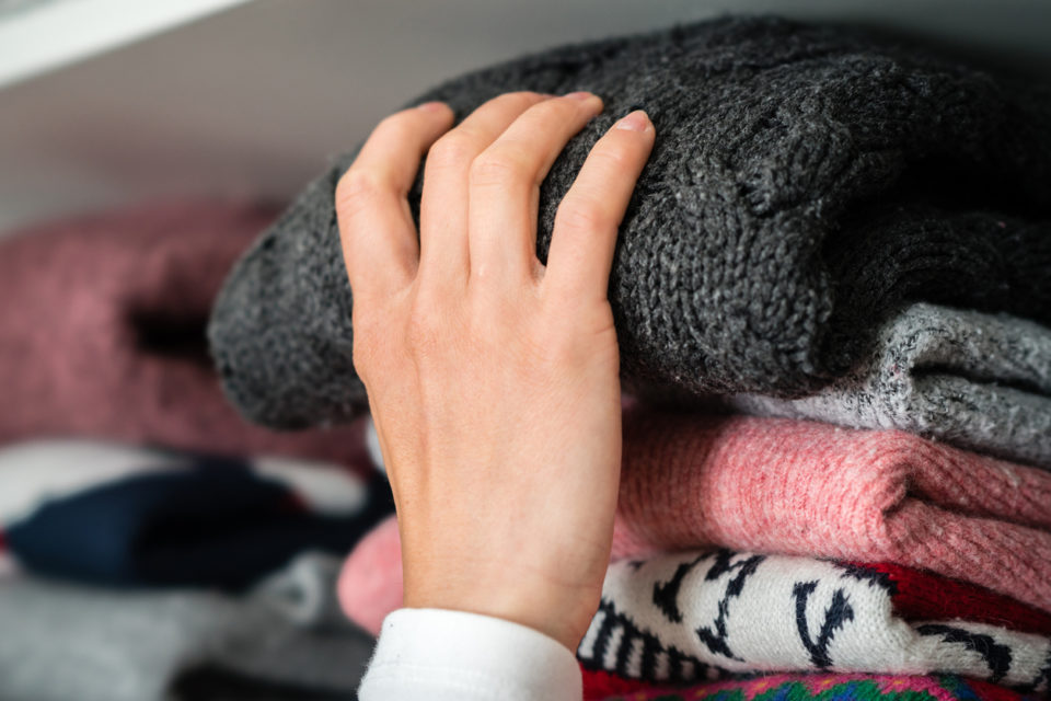 Woman is getting winter clothes out of the closet.