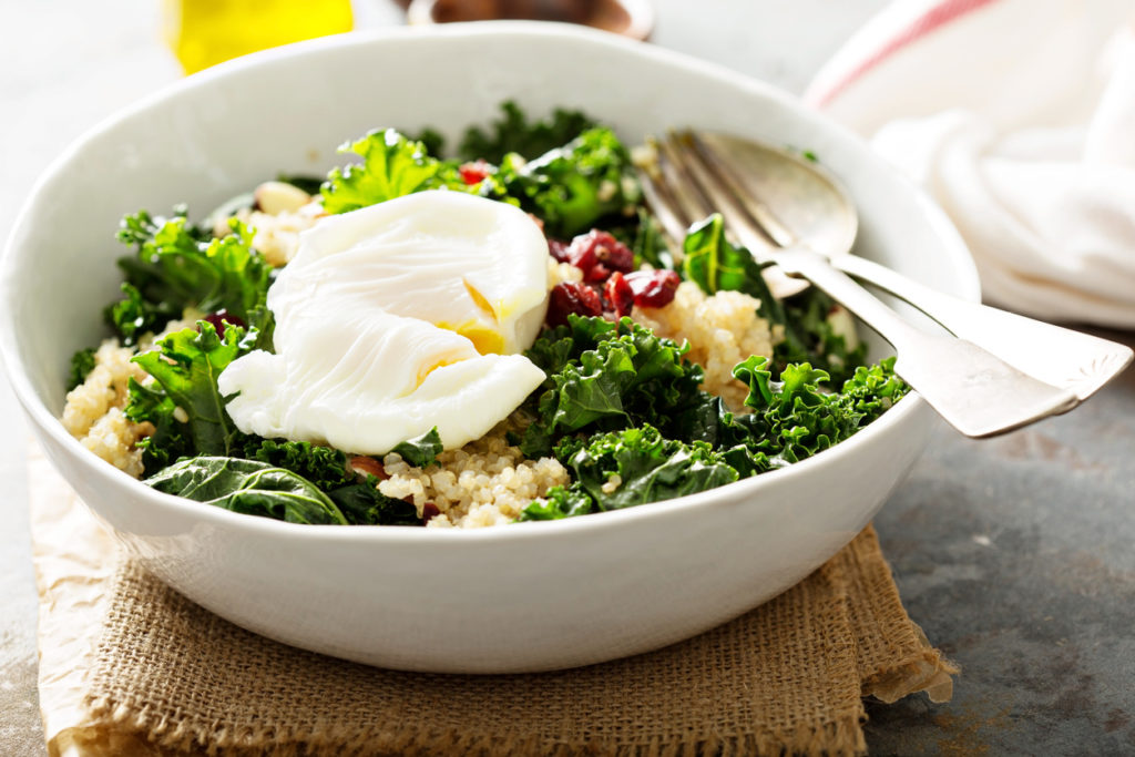 Healthy raw kale and quinoa salad with poached egg on top