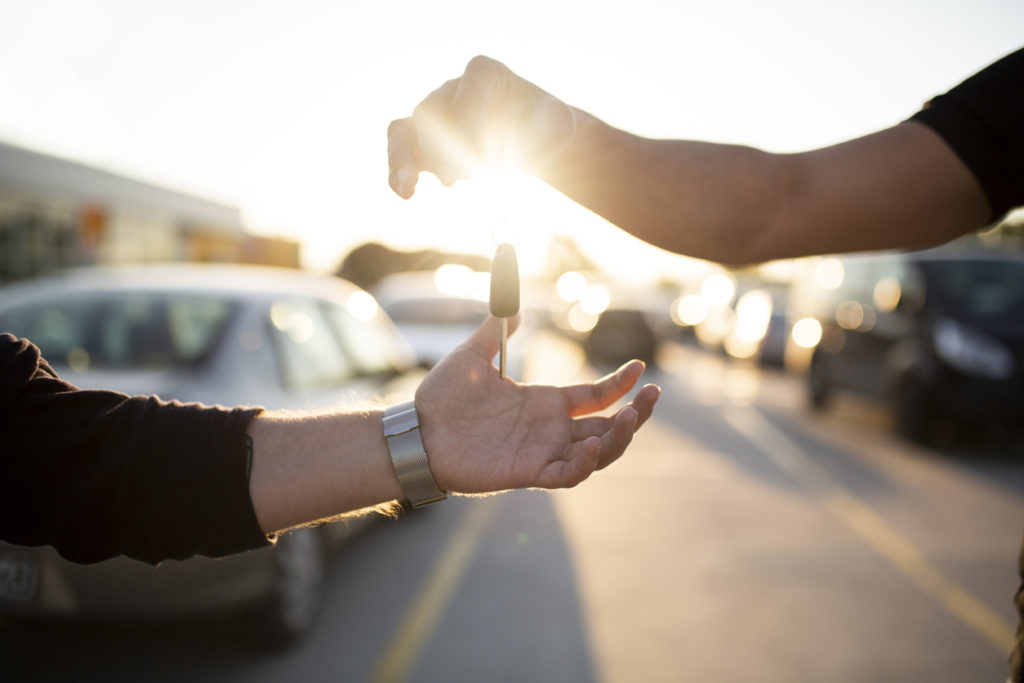 Salesman handing car key over to buyer