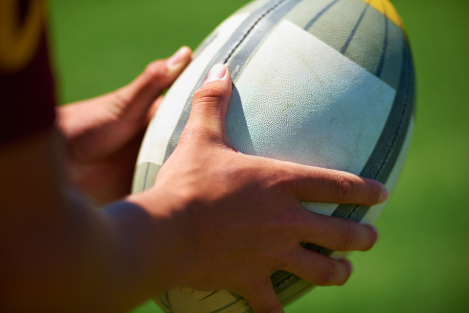 A close up of a rugby player holding a ball