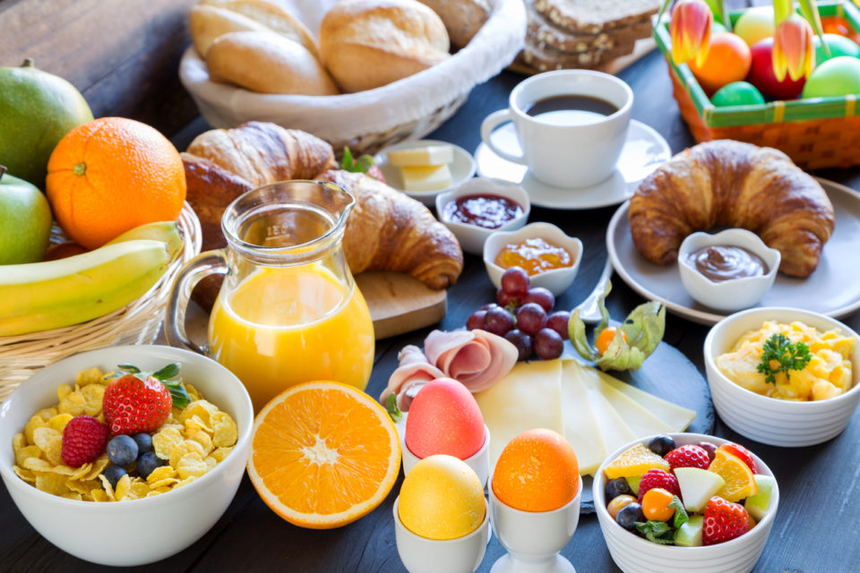 Easter brunch table with fruit, bread, coffee, and orange juice.