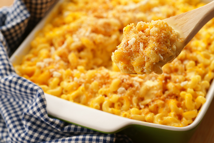 A spoonfull of homestyle baked macaroni and cheese with crispy breadcrumbs and shredded cheddar. Sharp focus on the contents of the spoon.