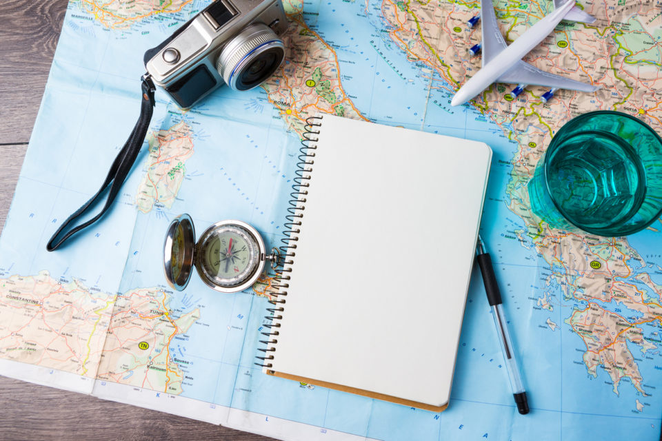 map, notepad, and other travel planning tools on desk